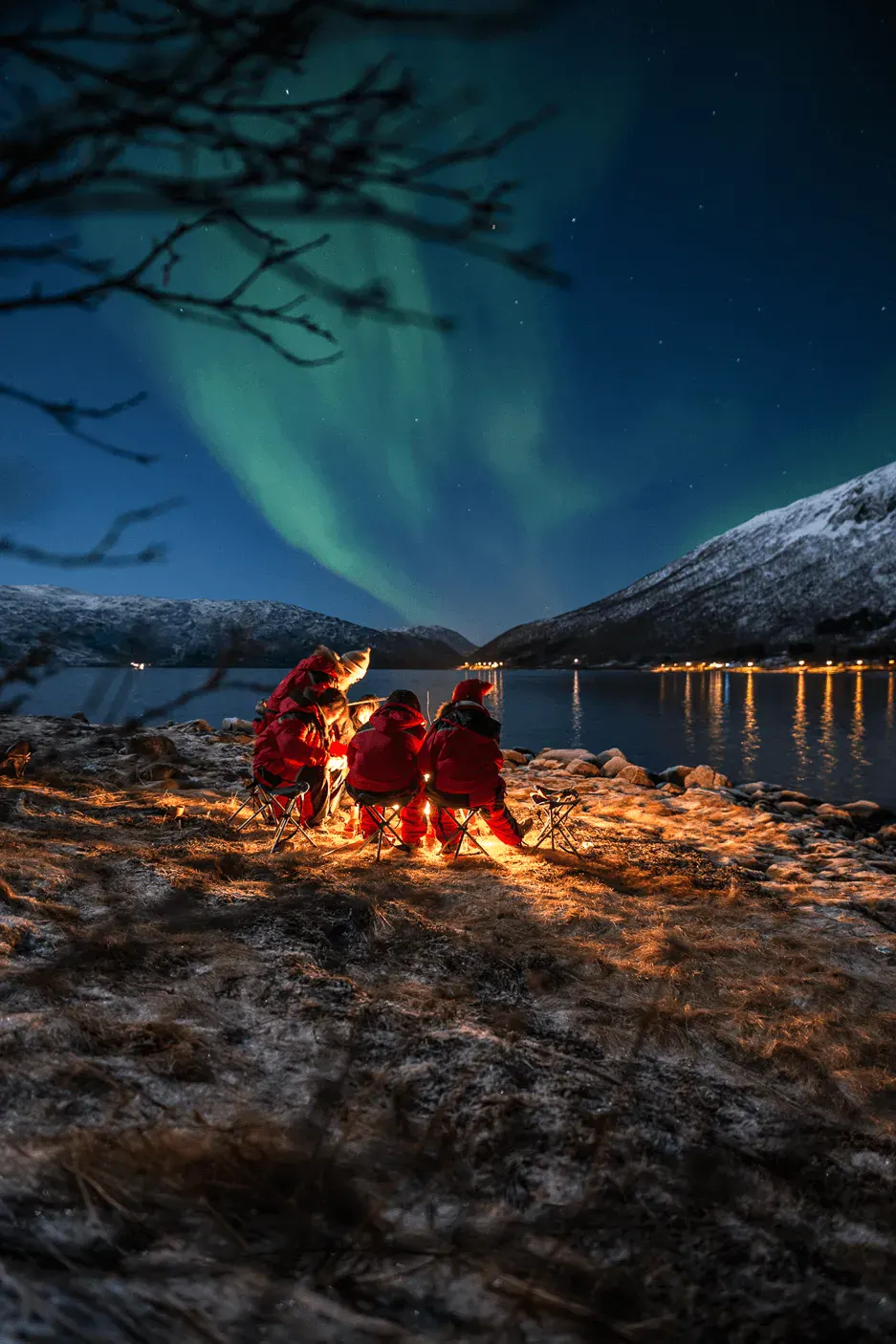Viajeros alrededor de una hoguera bajo las auroras boreales